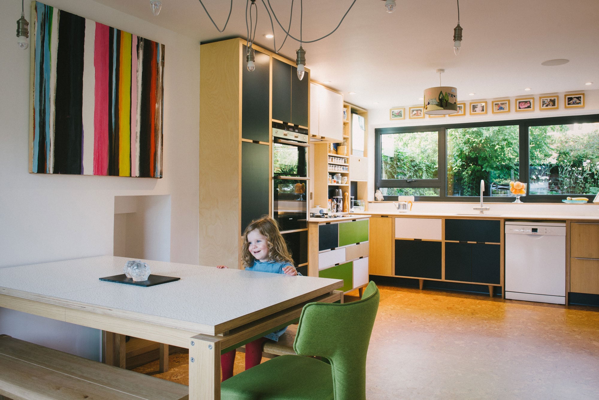 Little girl smiling in bespoke plywood kitchen