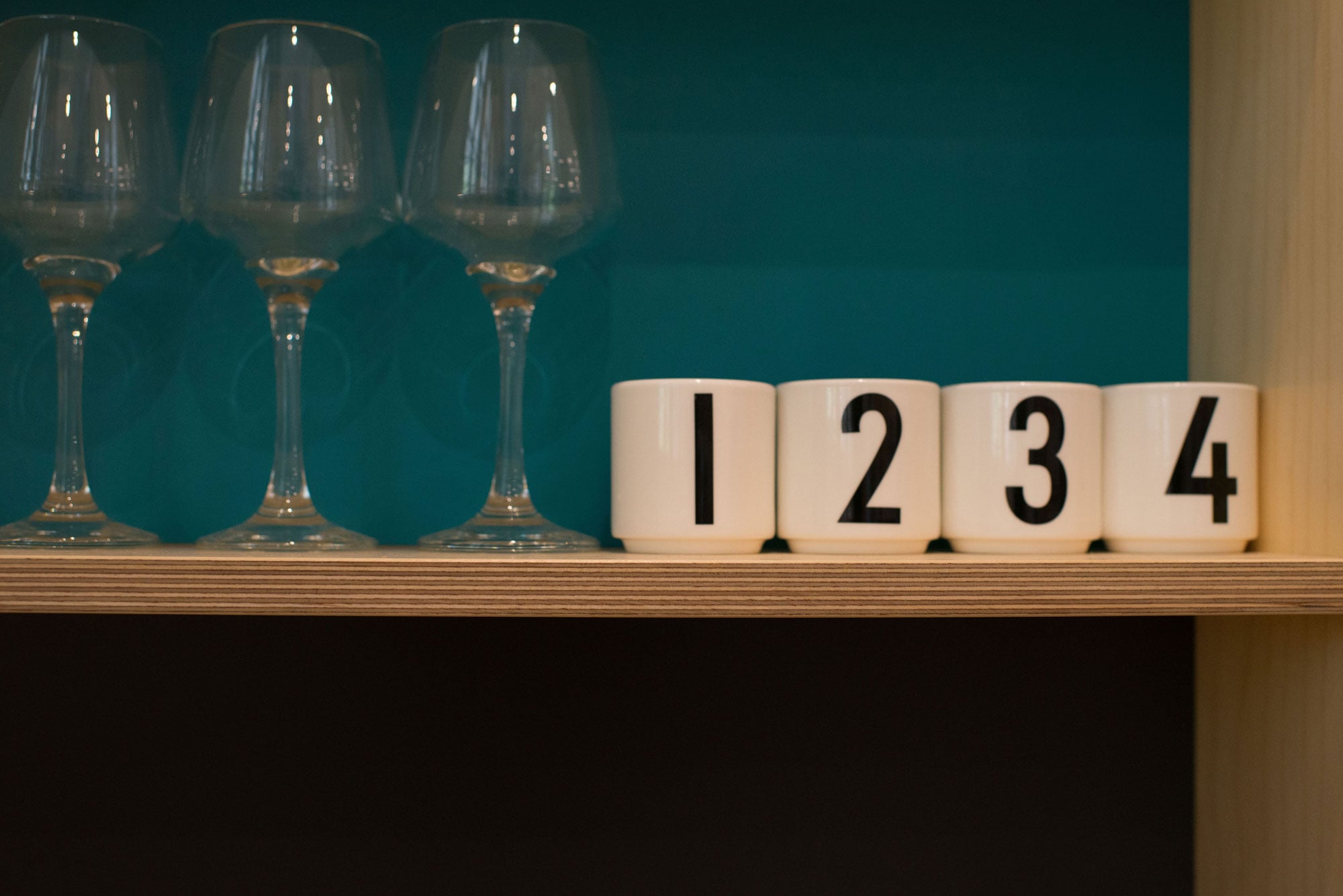 Numbered egg cups on plywood shelf.