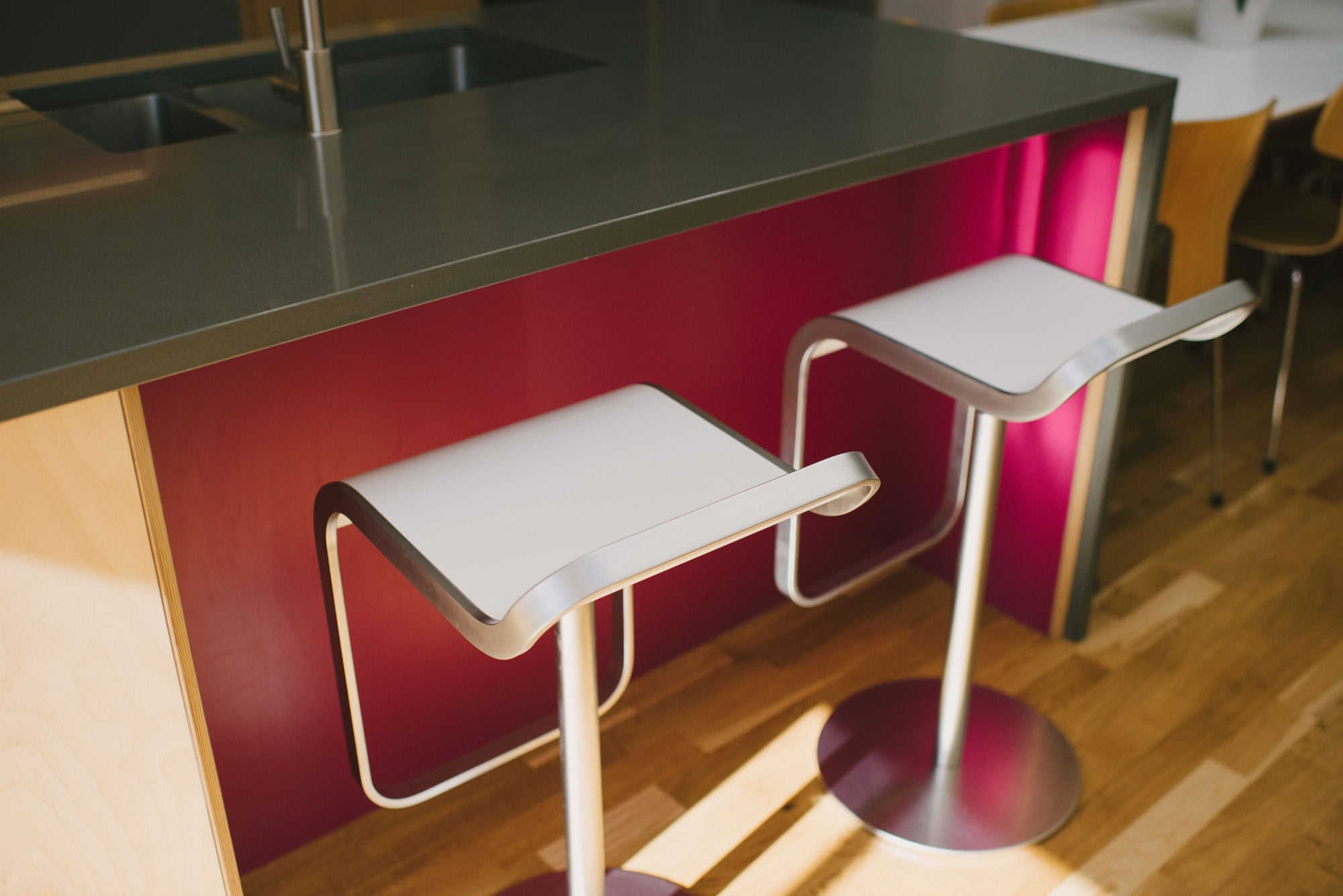 Breakfast bar stools at pink and grey plywood kitchen island unit