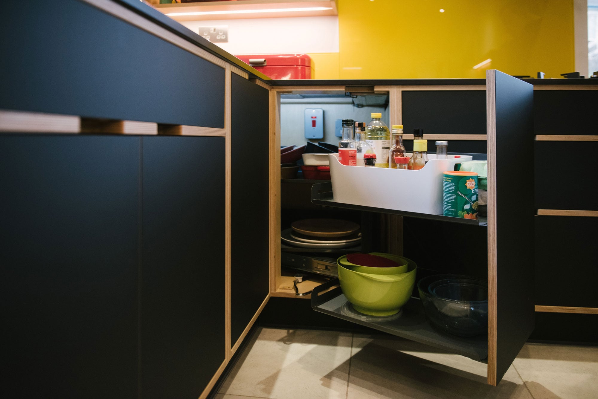 Pull Out Cupboard of Black Plywood Kitchen with Yellow Splashback