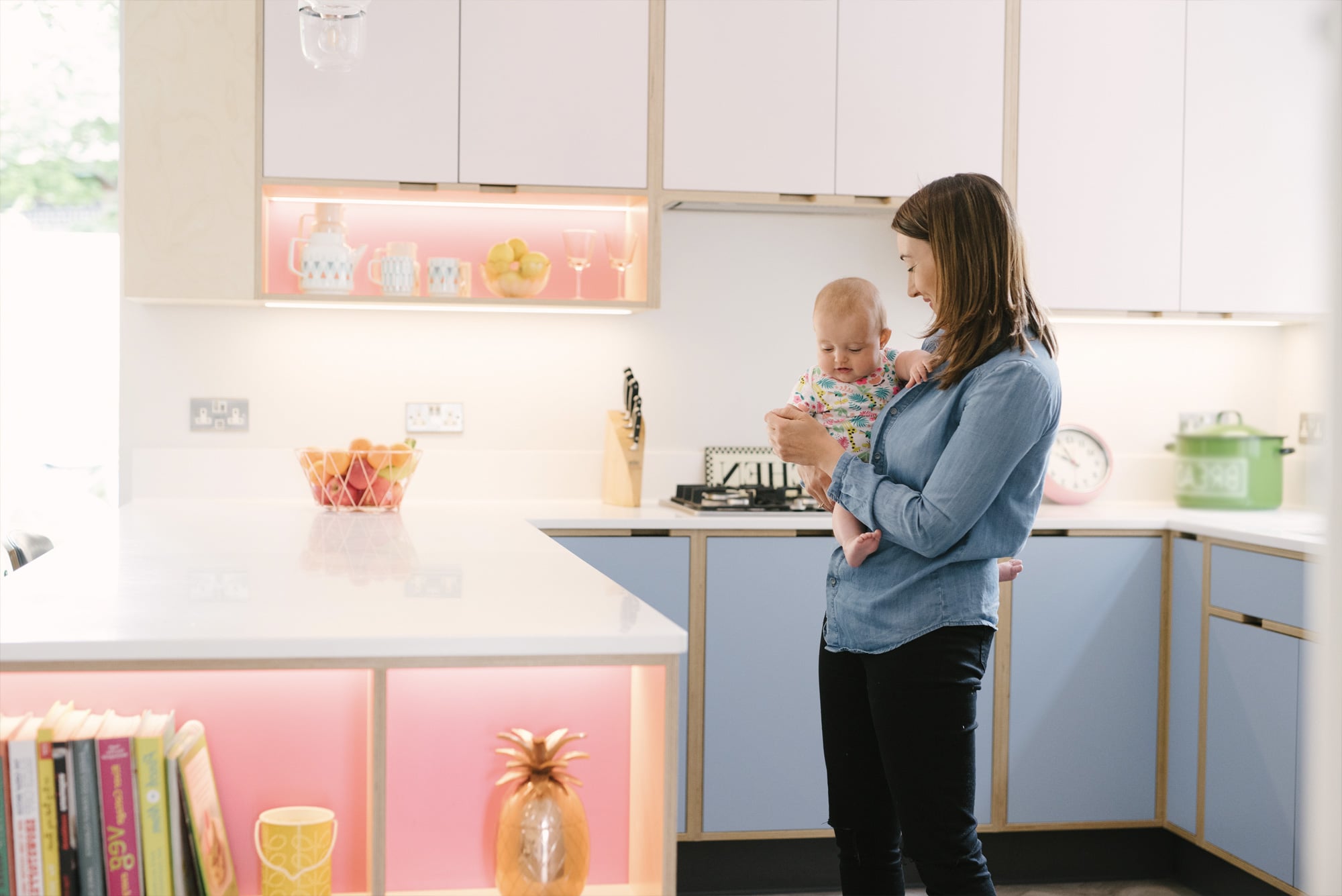Mother and child in pink and blue plywood kitchen