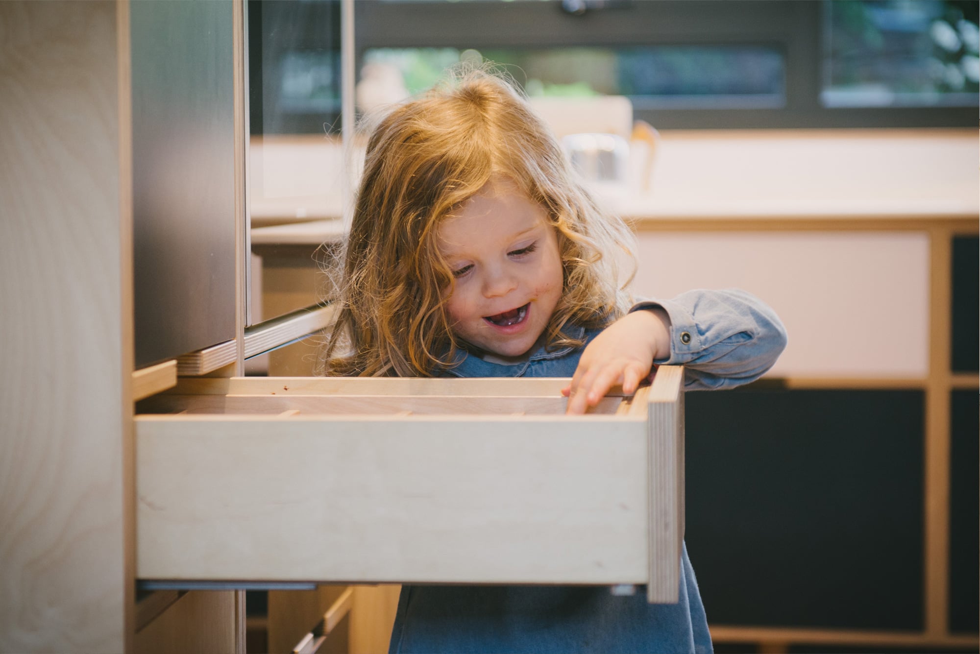 Little girl looks into plywood drawer