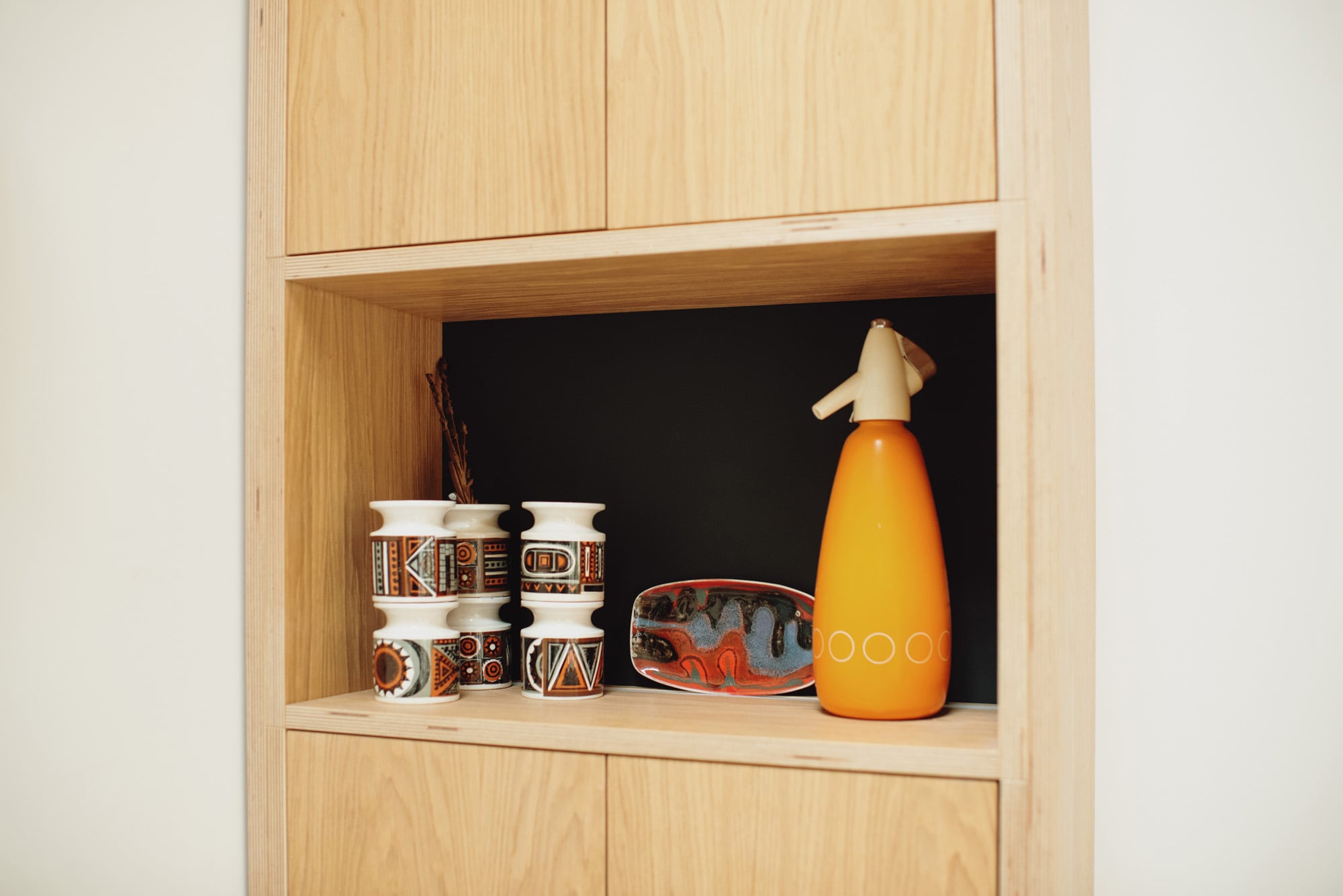 Open shelf in cabinet showing mid mod accessories