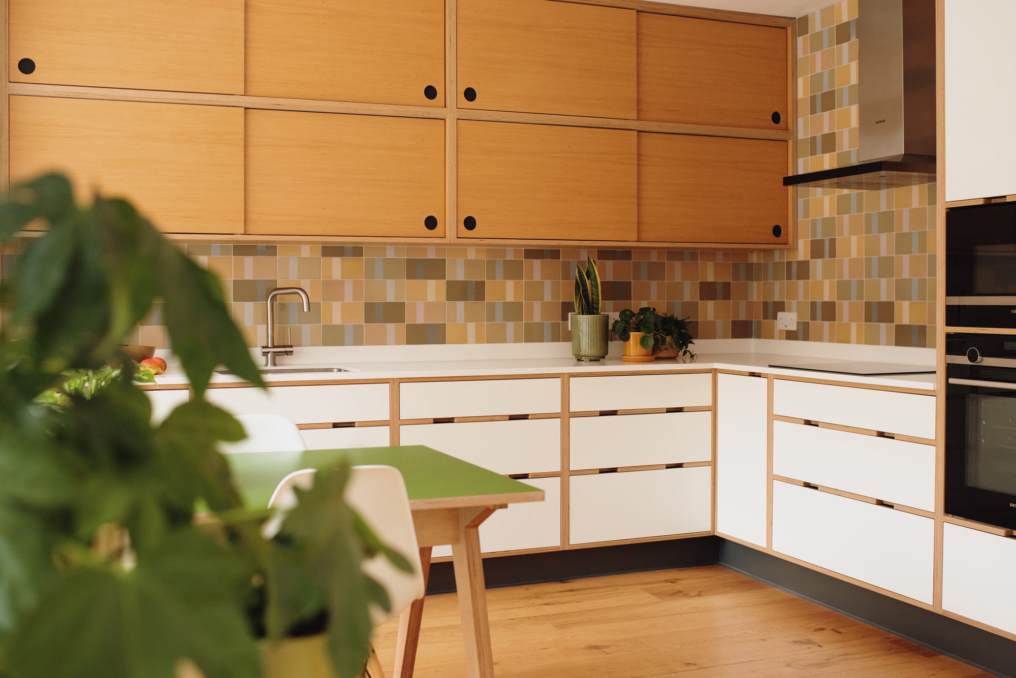 Close shot of white plywood kitchen with double layer of oak sliding wall cupboards