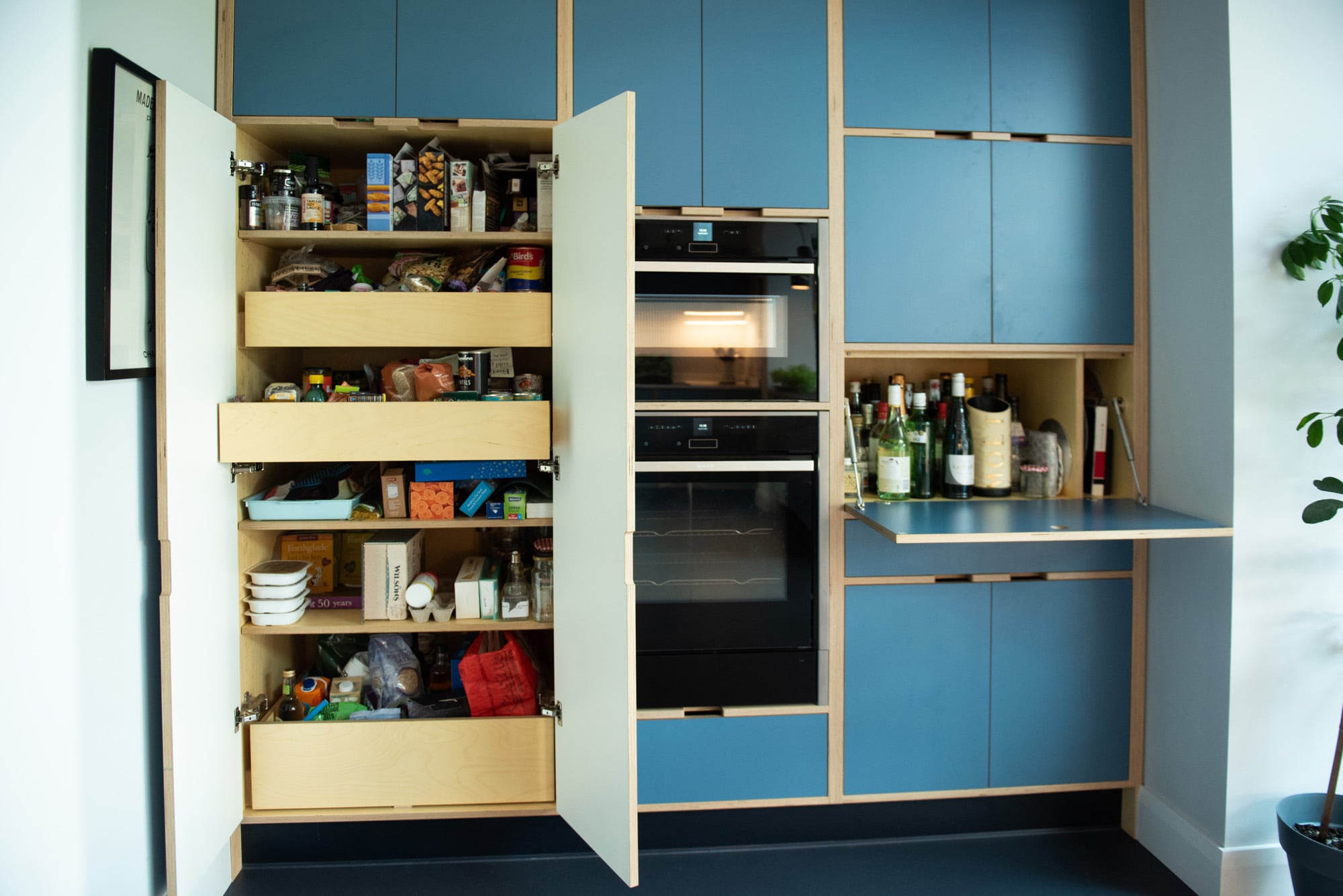 open tall cupboards in 1930's style plywood kitchen
