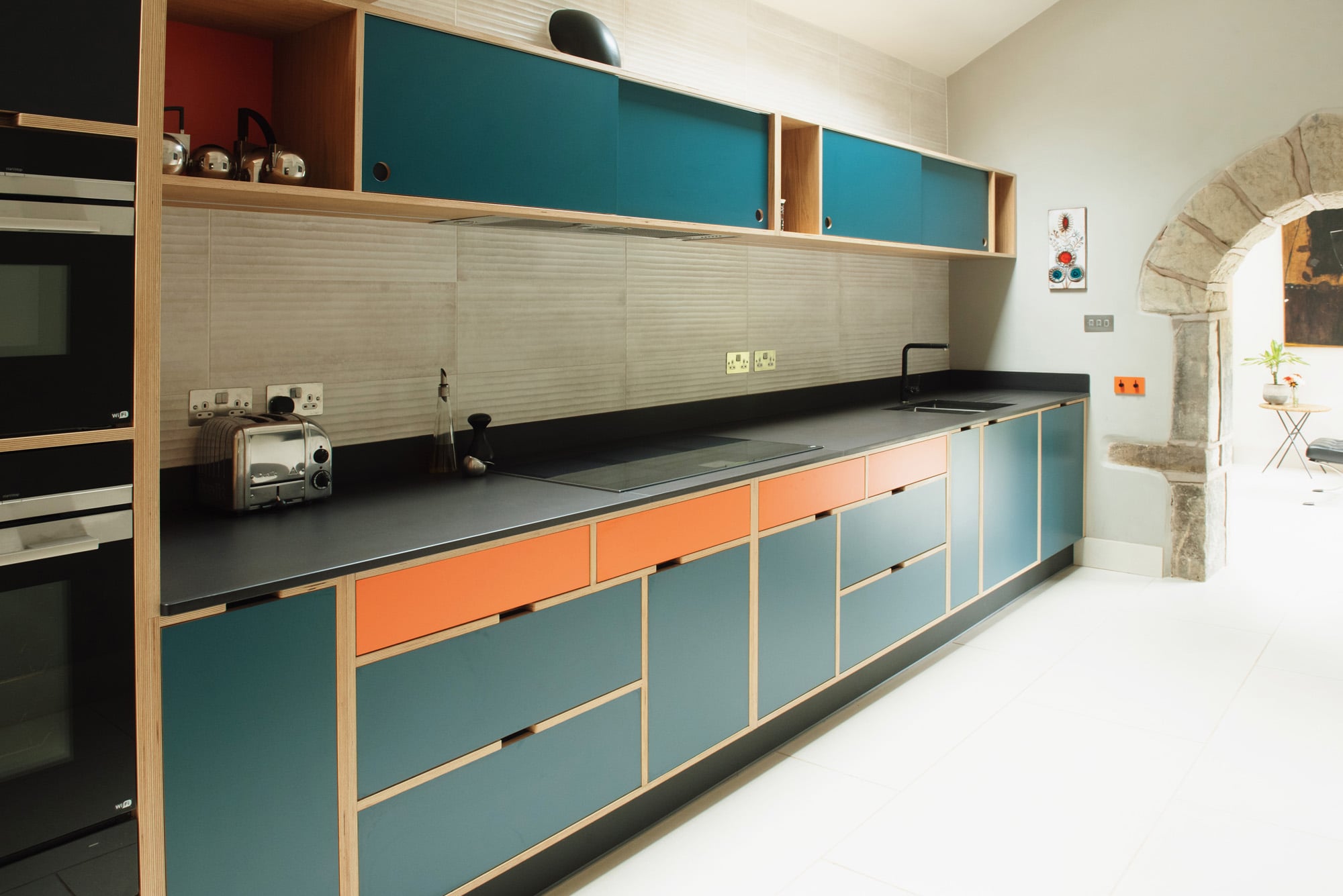 full view of galley blue and orange bespoke kitchen