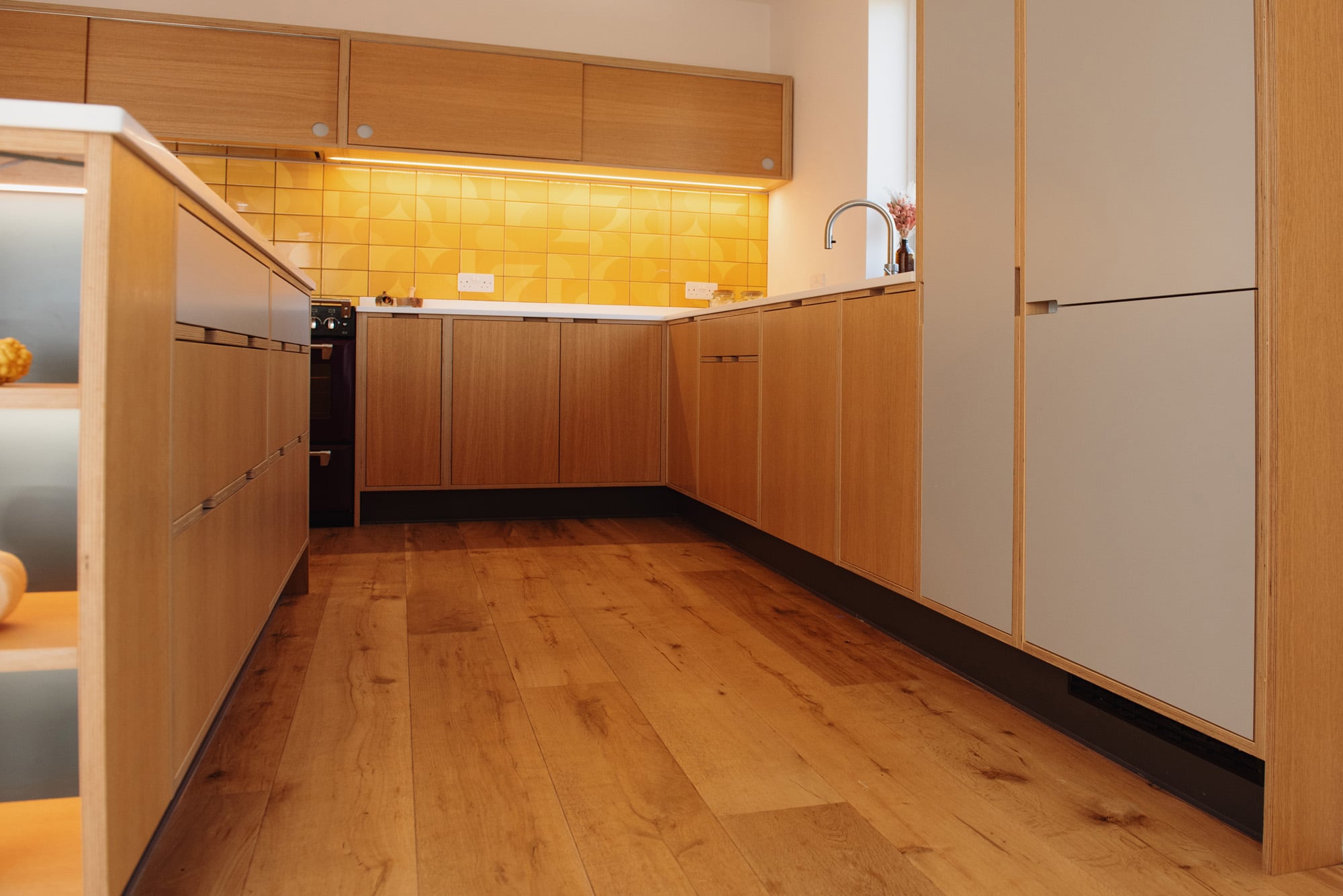 grey laminated tall kitchen units next to Oak veneered base units
