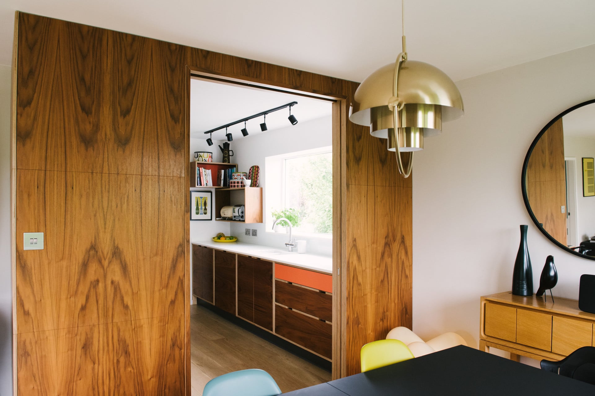 a mid century modern kitchen in walnut veneer with orange highlights