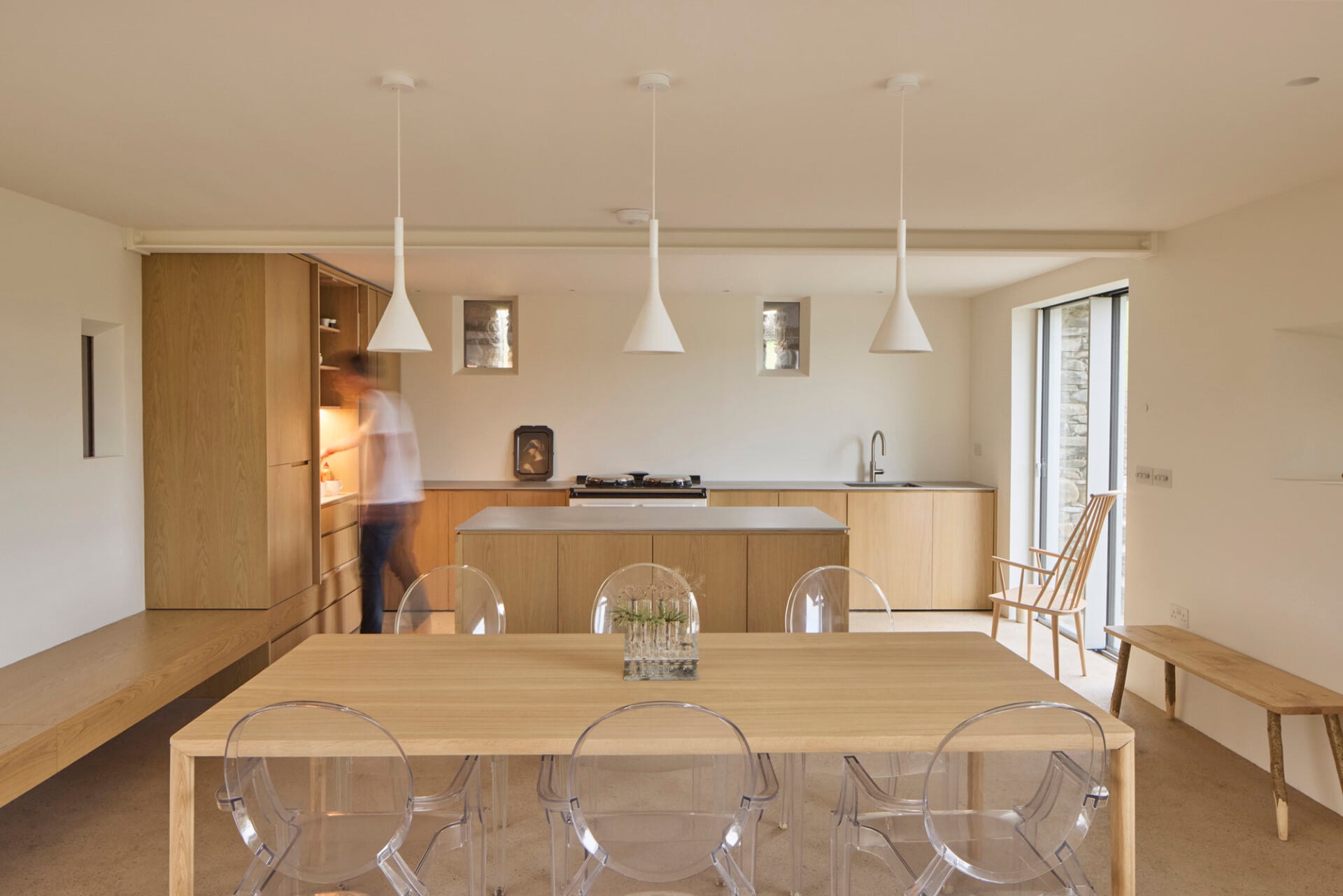 Open-plan barn dining room with modern wooden cabinetry, pendant lights, and mixed seating