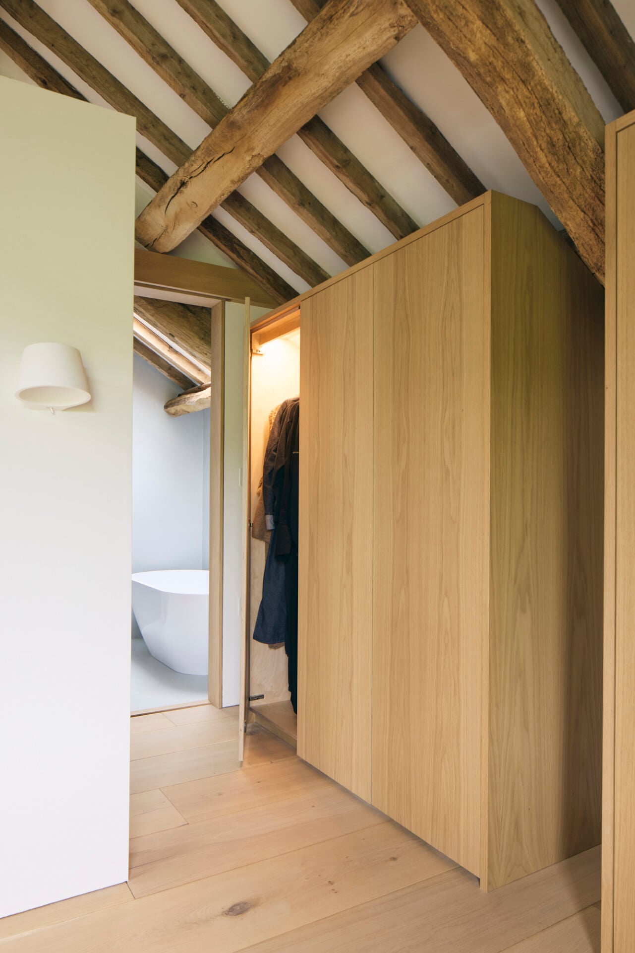 Fitted oak wardrobes in barn conversion with exposed beams and pitched ceiling