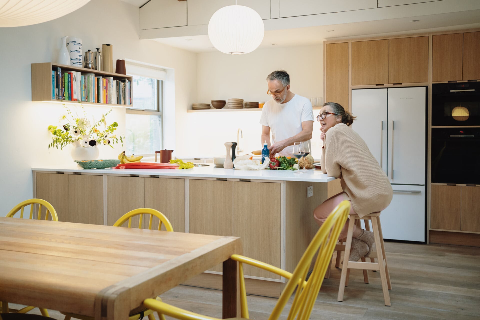 Family kitchen with light oak veneered plywood cabinets, breakfast bar, and yellow chairs