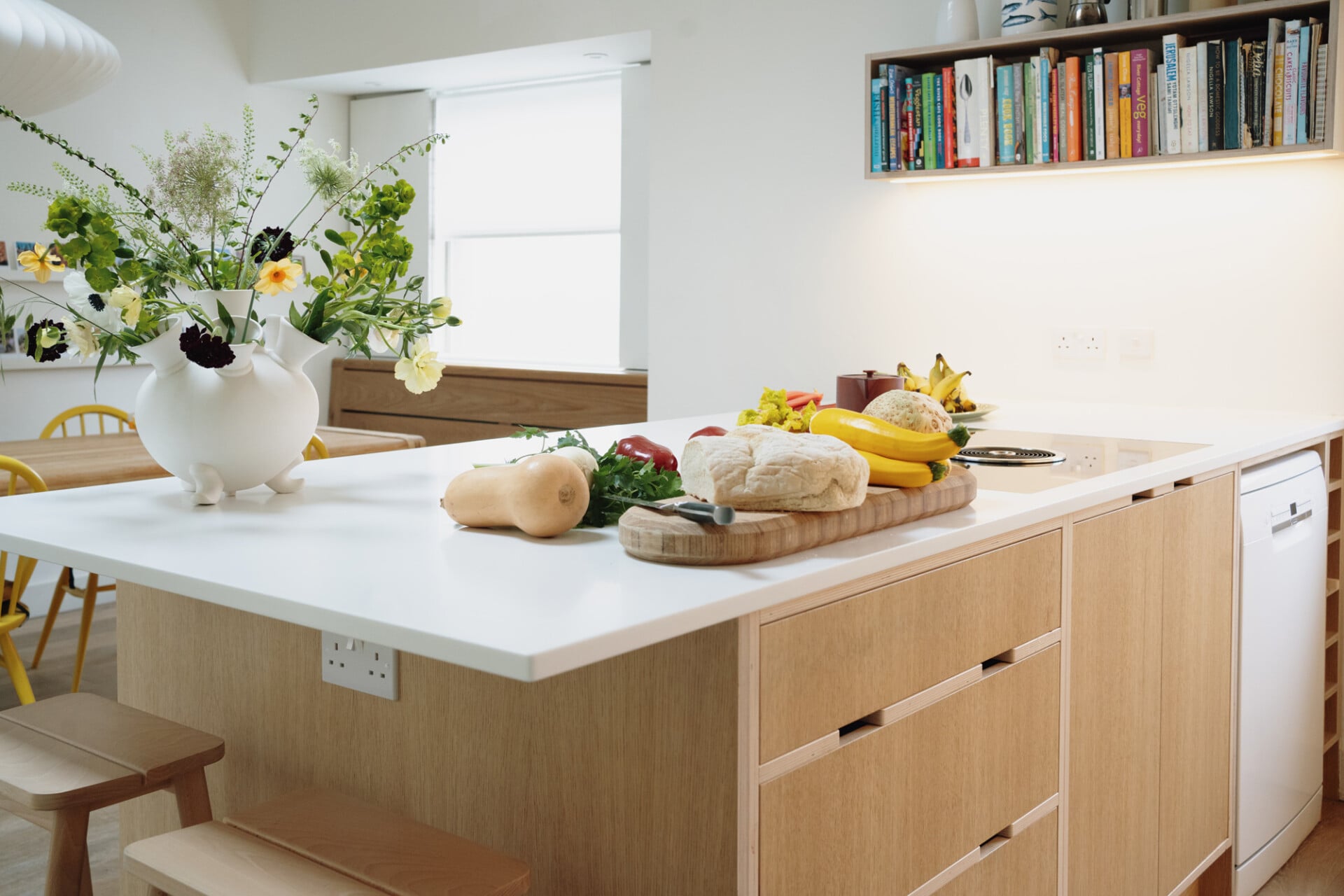 Light wood kitchen with open shelving, white countertops, and island in a calm London home