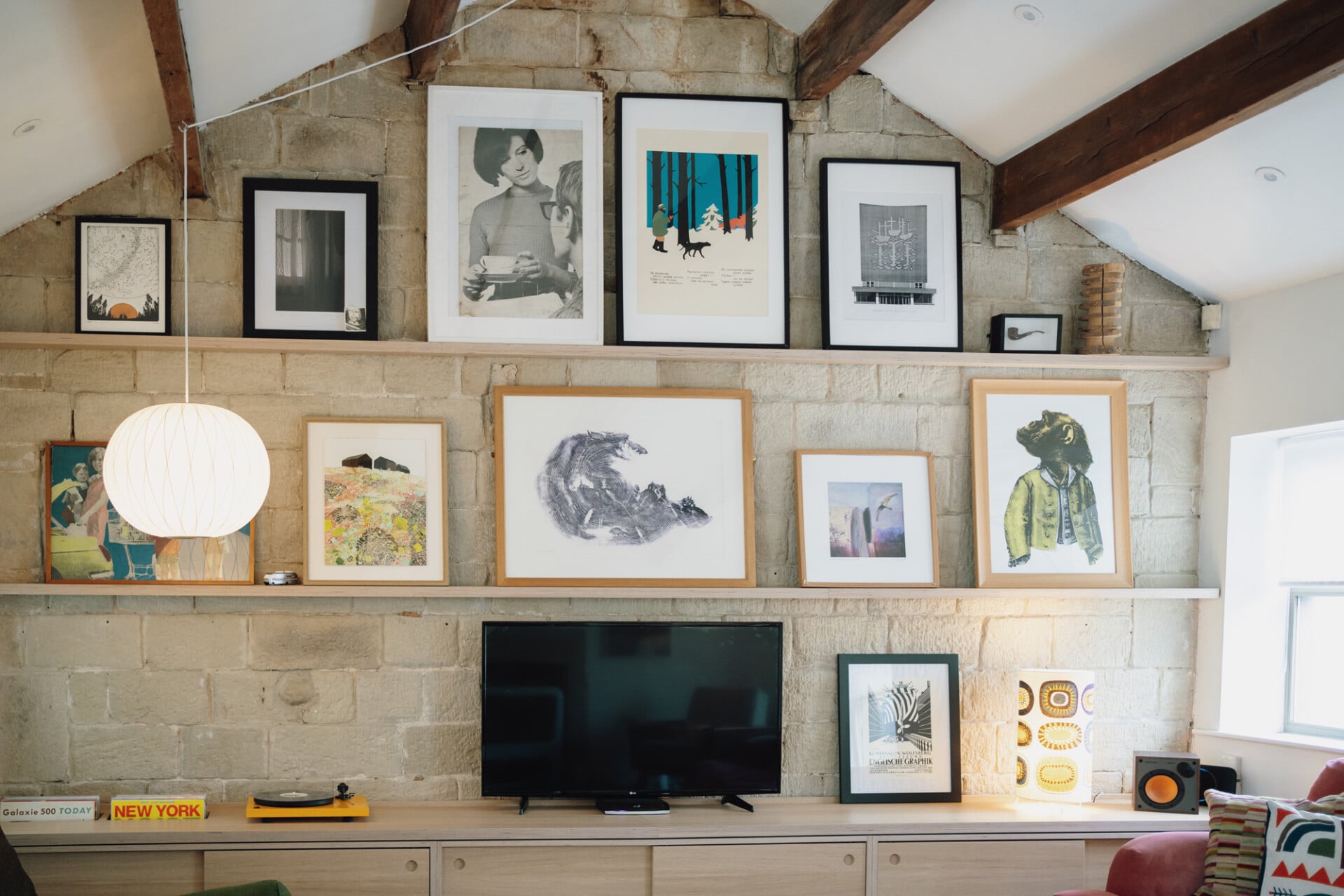 Rustic living room with stone wall, wood beams, and gallery wall of framed art