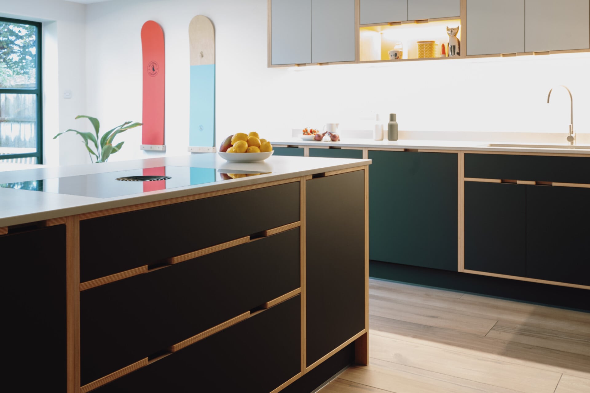Handleless plywood kitchen island with black fronts and exposed wood trim