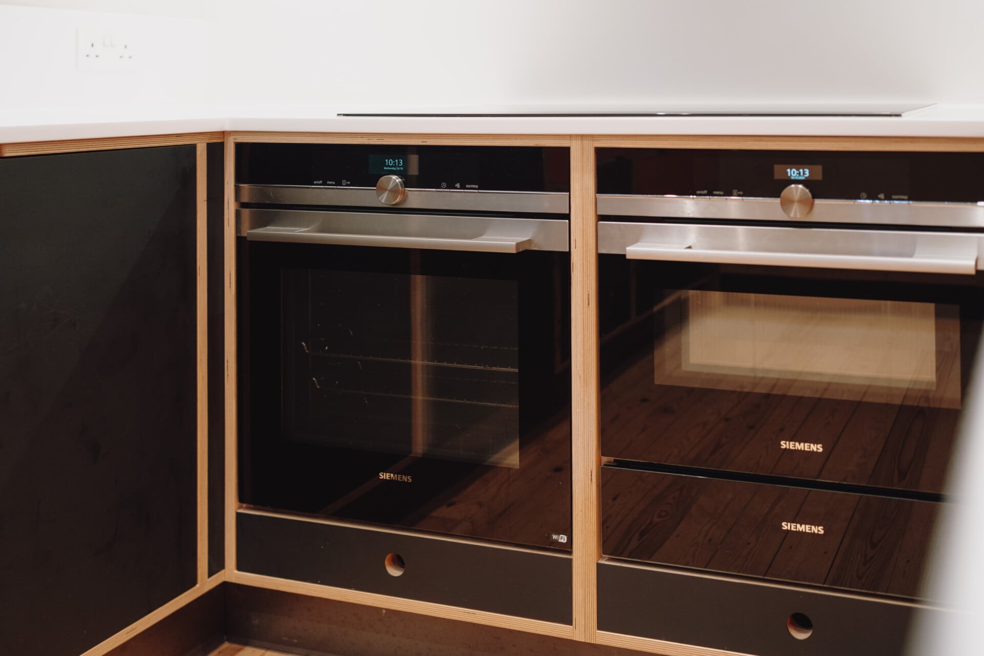Herb planter plywood kitchen with double oven and wood-trimmed fronts