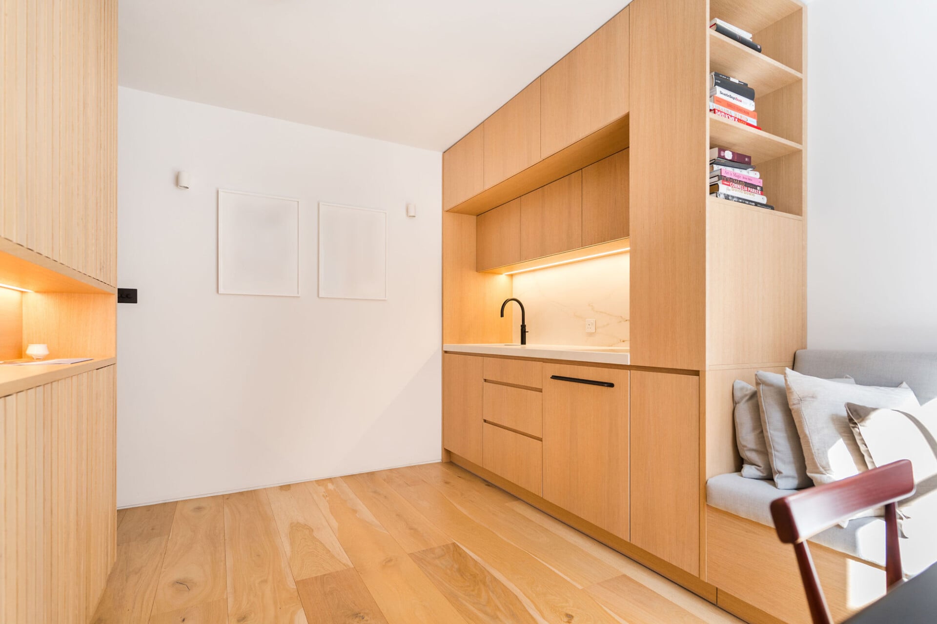 Compact oak kitchen joinery with open shelving and built-in banquette seating