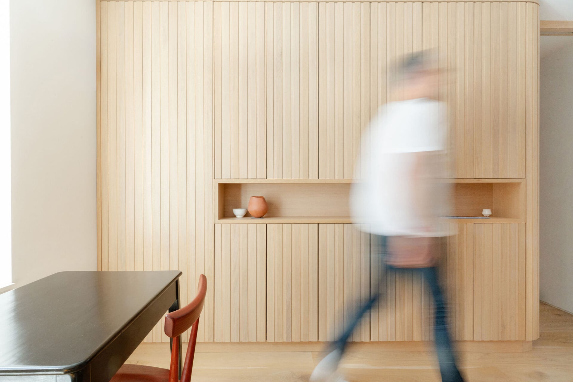 Full-height oak joinery with slatted panel detail and integrated open shelf