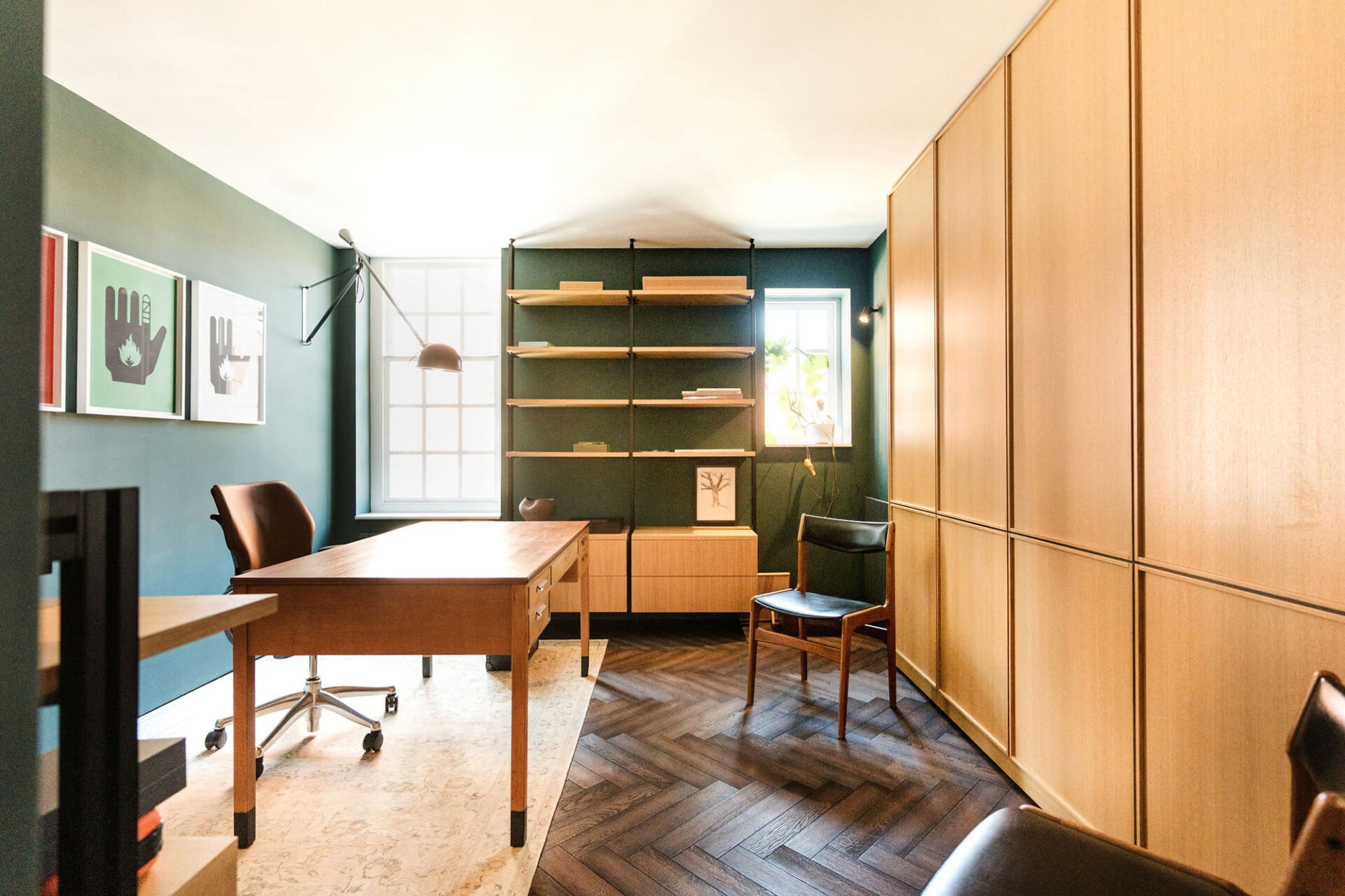 Home office with floor-to-ceiling panelled oak storage and green painted walls