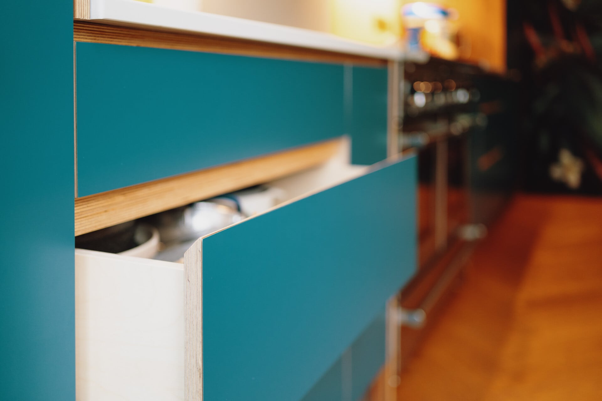 Close-up of mint green kitchen drawer with integrated wooden handle