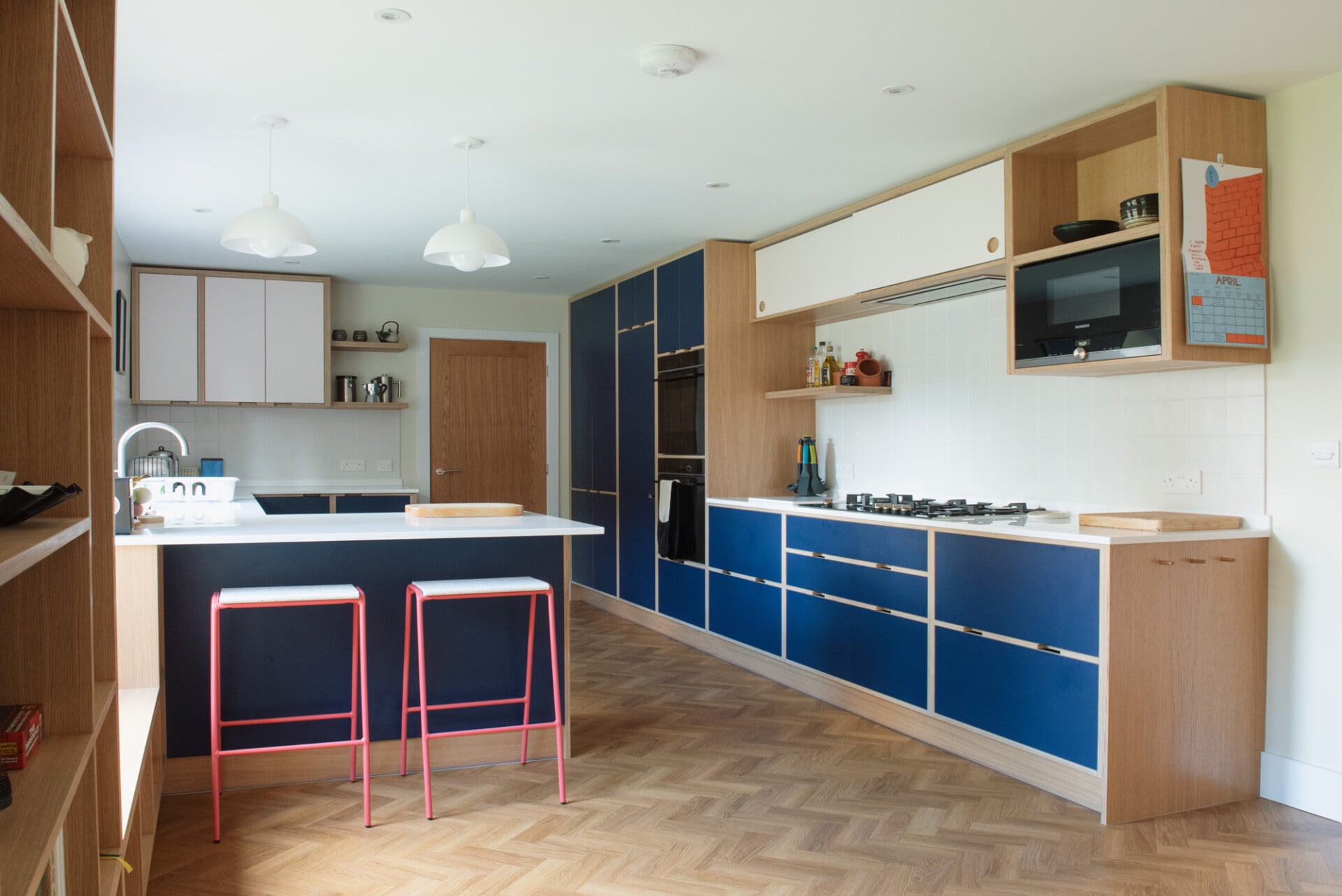 Modern blue plywood kitchen with U shape, galley wall layout and pendant lighting