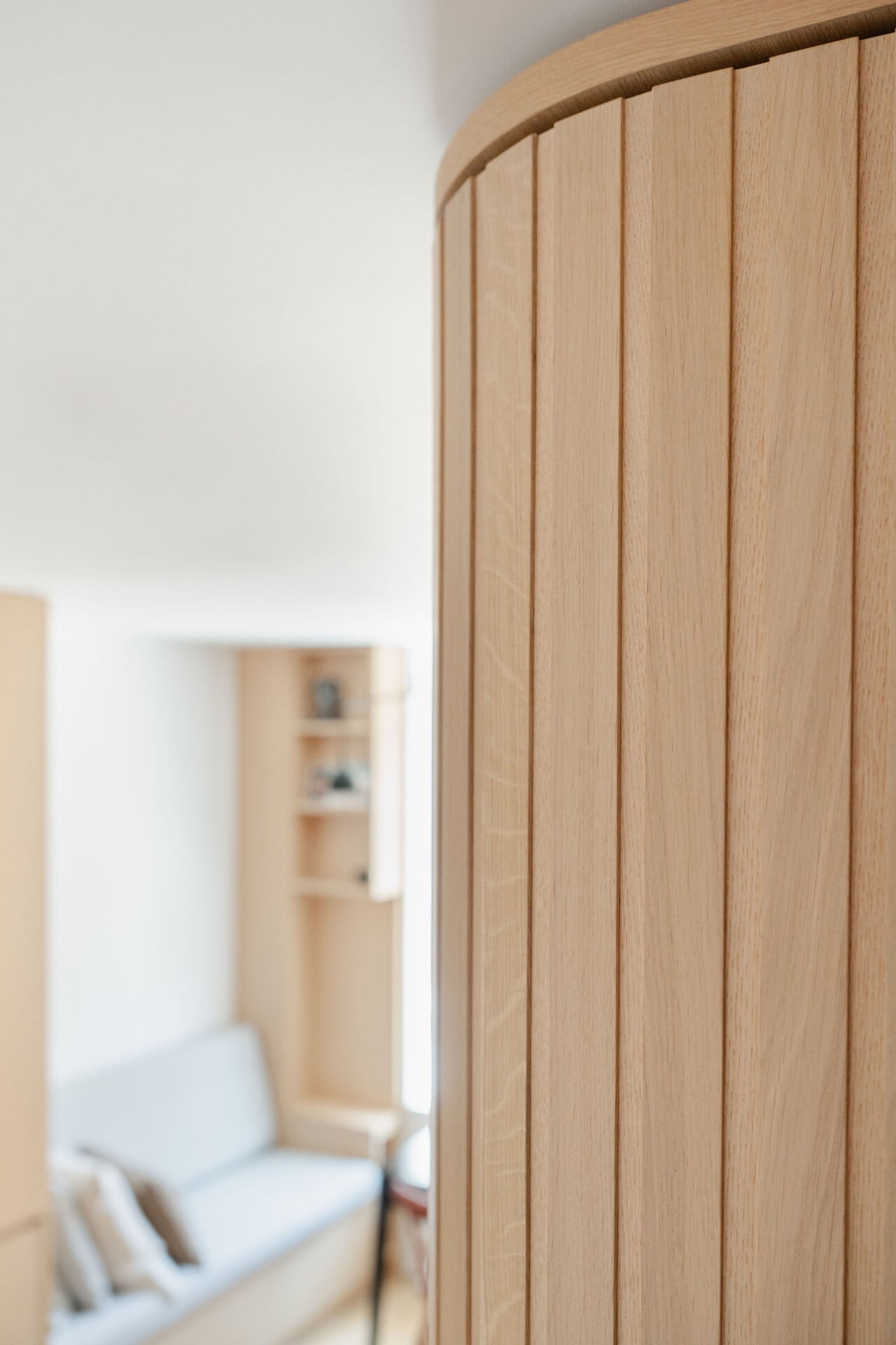 Tall plywood storage with smooth curved end panel for hallway circulation
