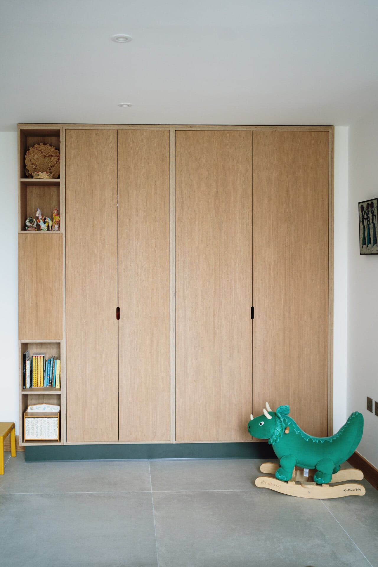 Children’s storage with pale grey floor and full-height fitted plywood storage wardrobe