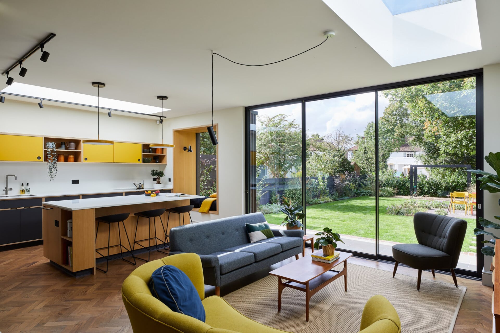 Open-plan plywood kitchen and living space in London with yellow accents and garden access