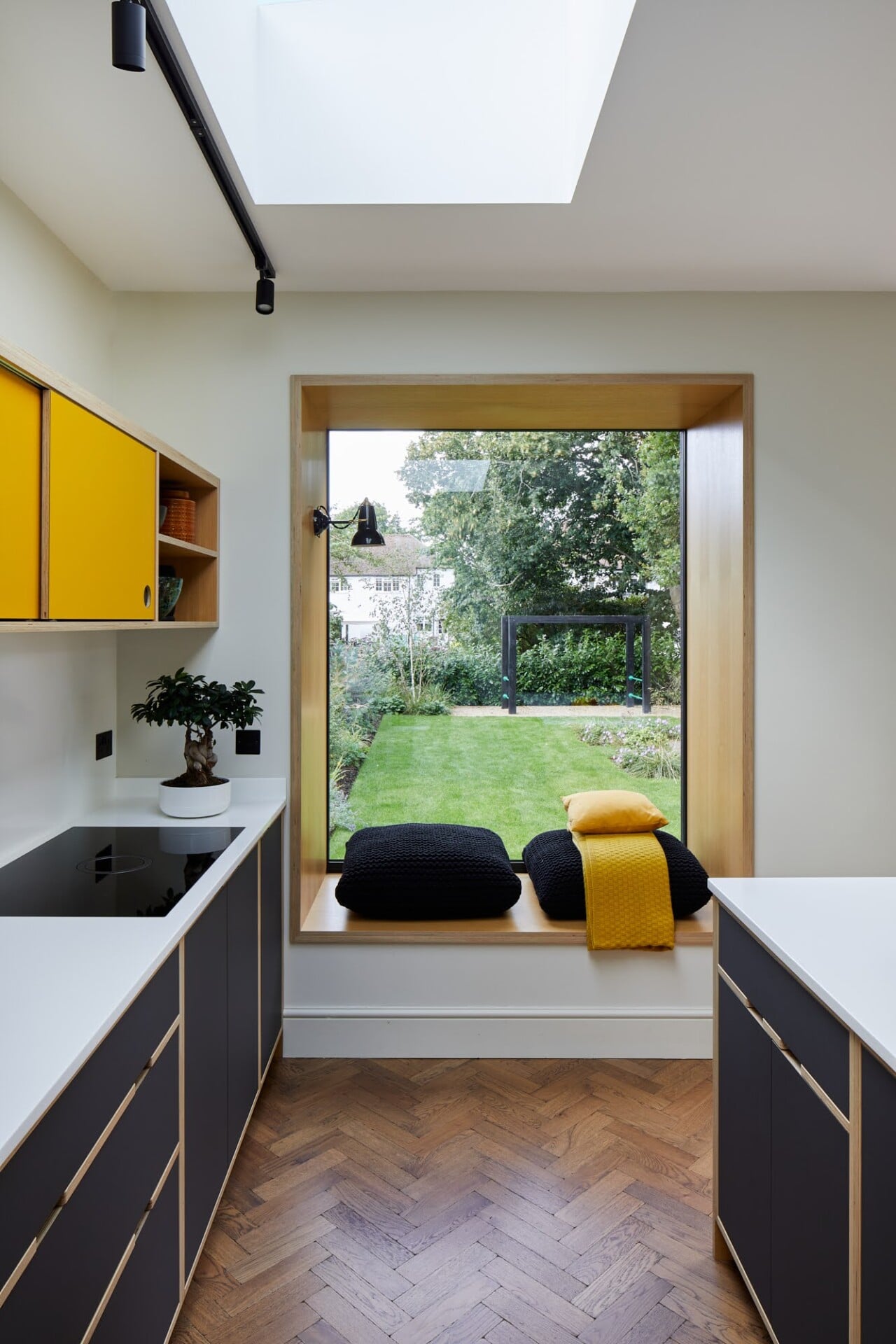 Small plywood kitchen corner in London with yellow cabinets and window seat