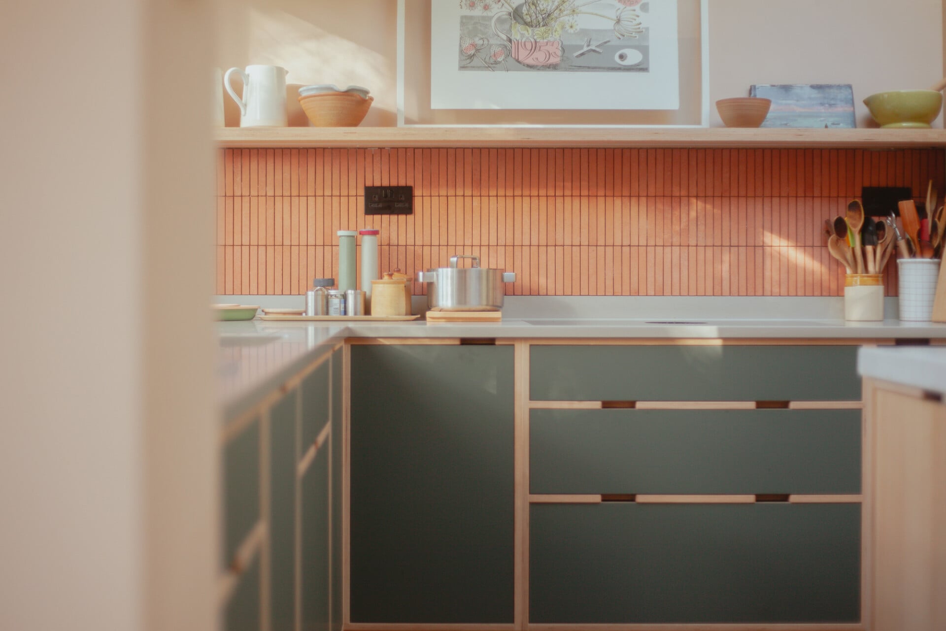 Cosy pink and green plywood kitchen in London with corner layout and natural light