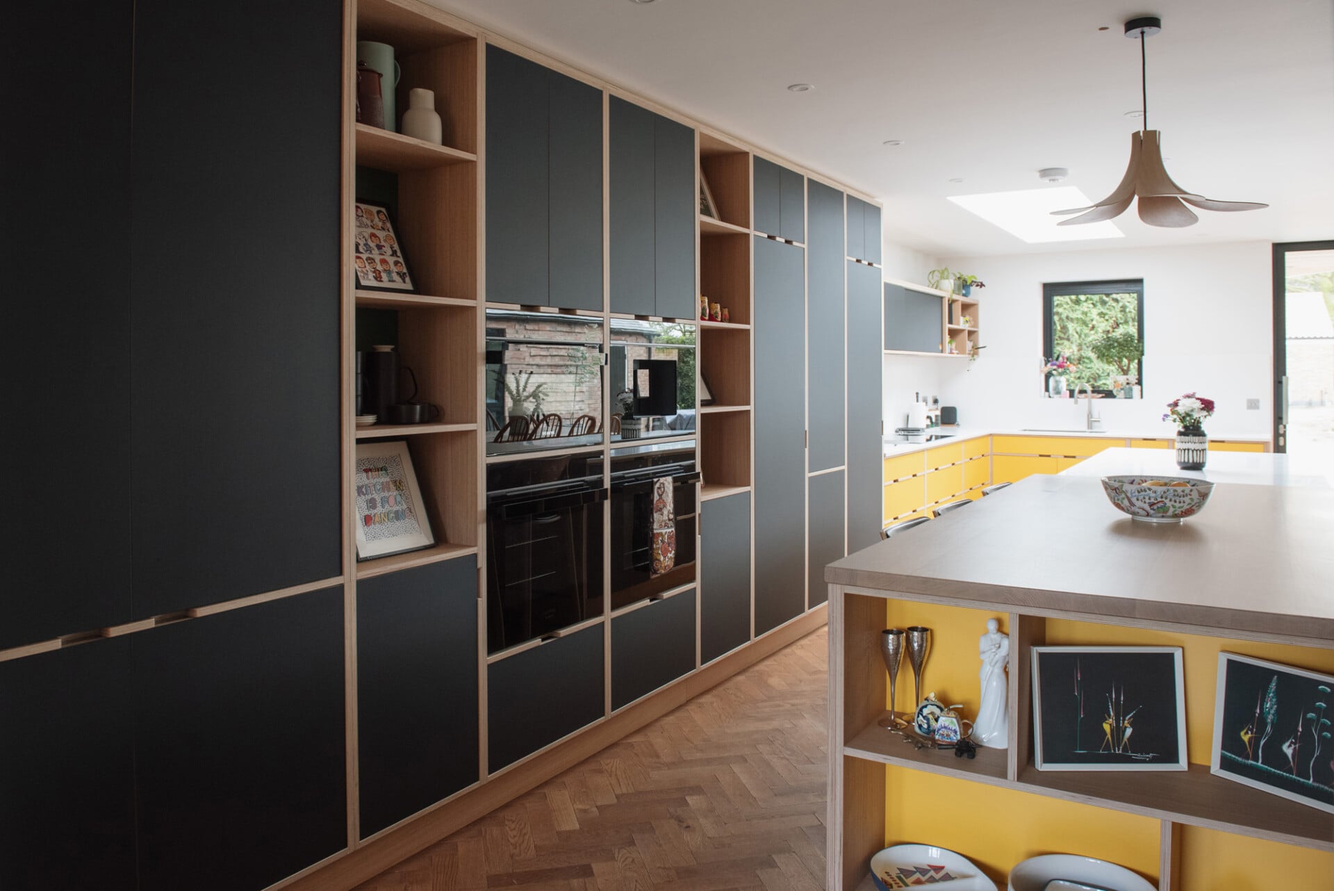 Spacious family kitchen with large island, colourful shelving, and yellow cabinets
