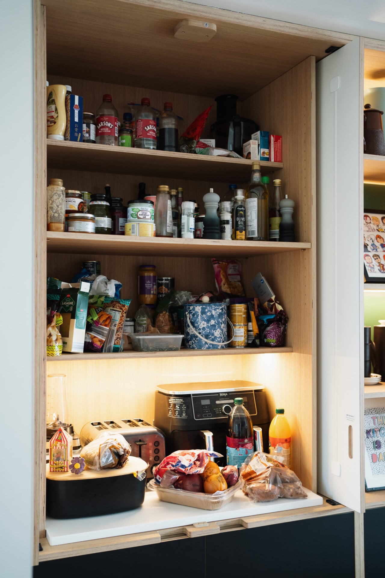 Hidden pantry and coffee station in colourful London kitchen with open shelving