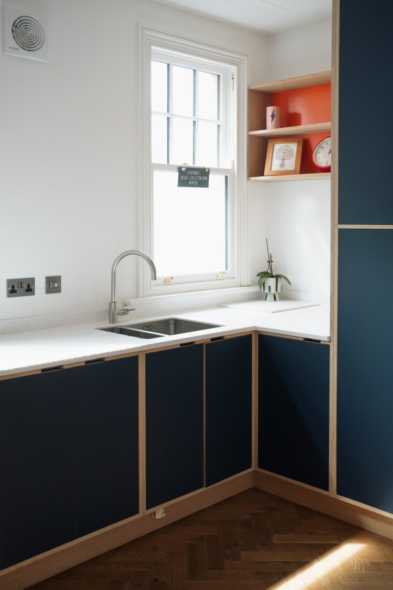 Compact kitchen with corner sink, navy cabinets, and white worktop in London home