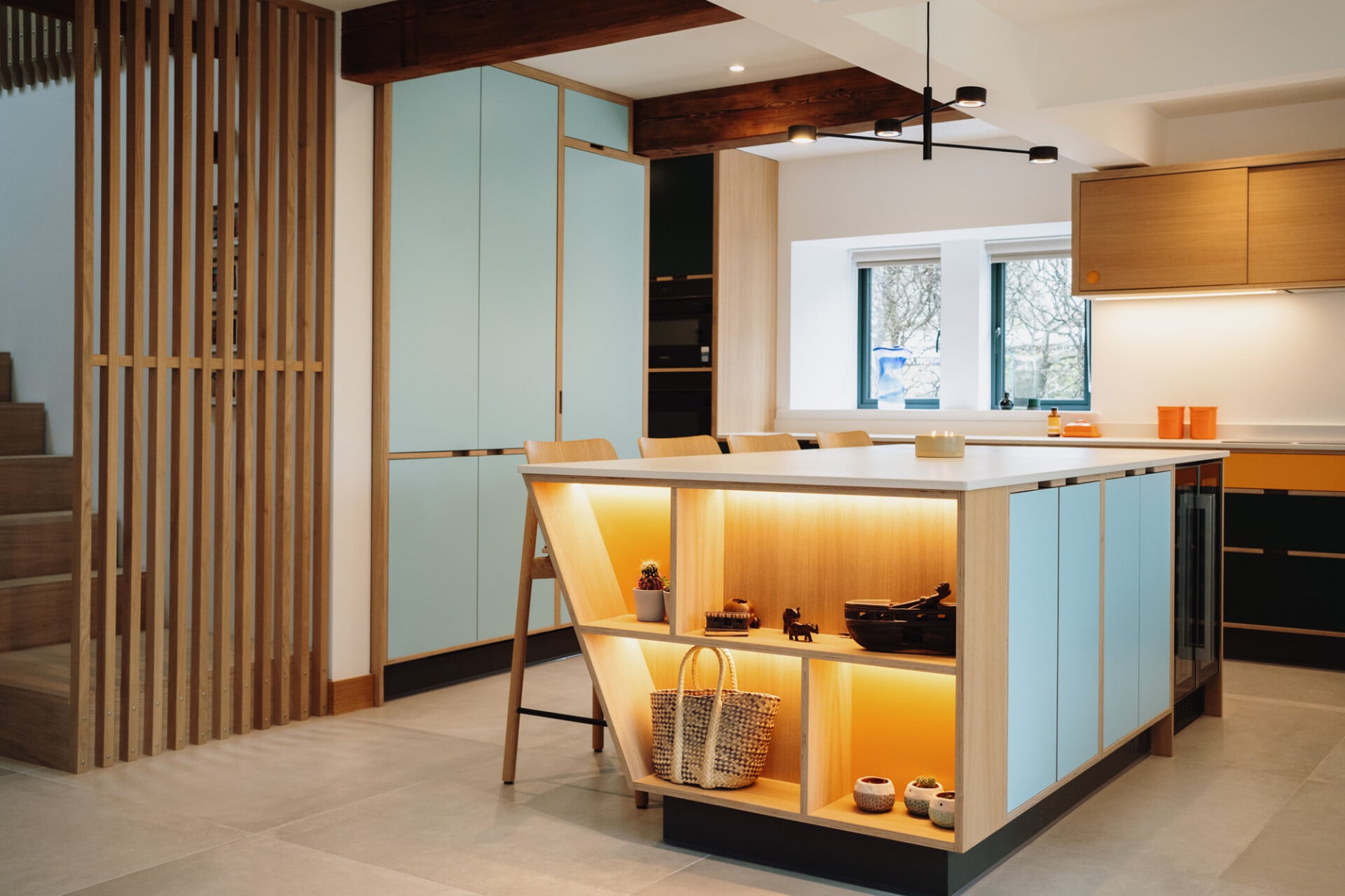 Bright family kitchen with colourful island, exposed beams, and open shelving