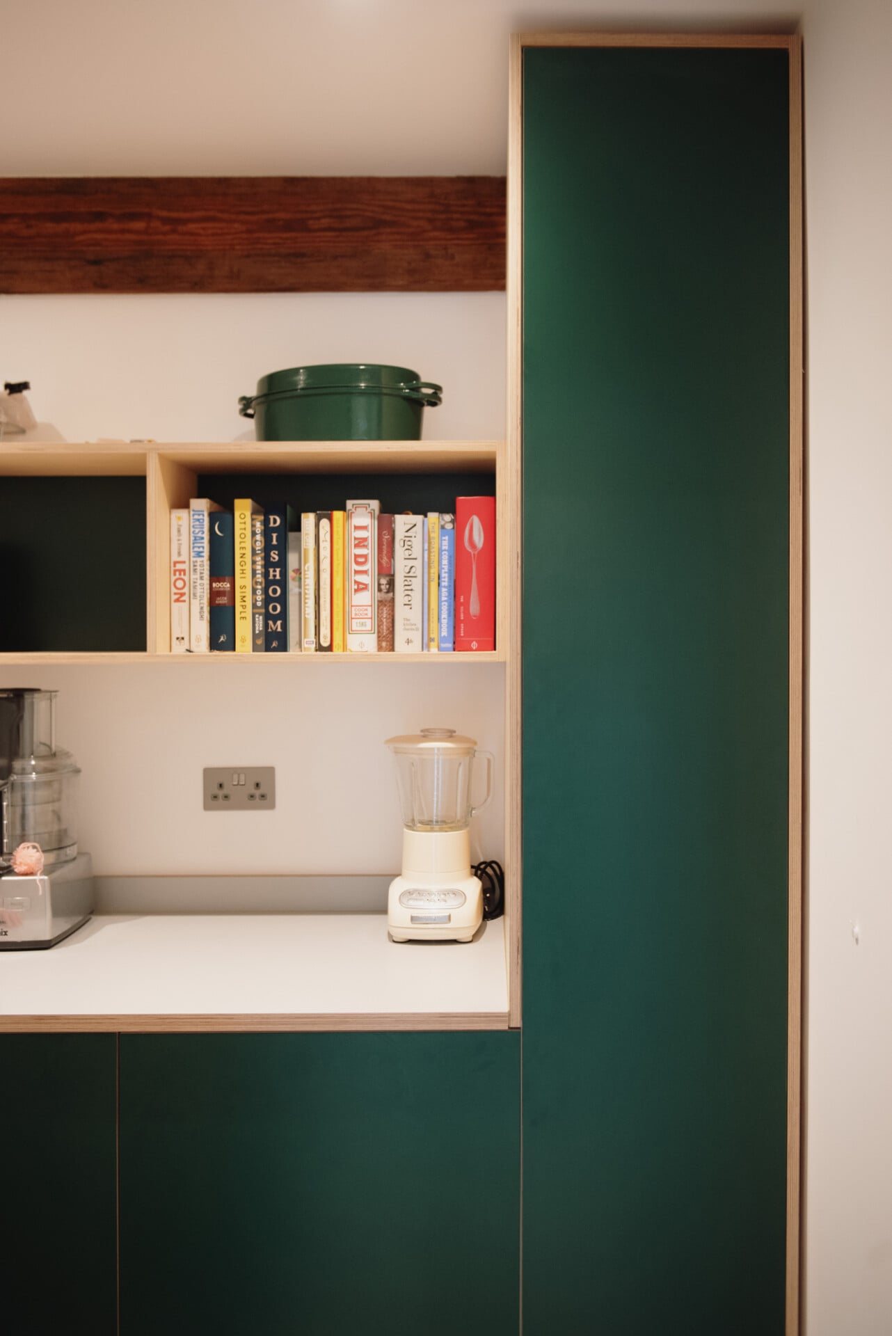 Colourful kitchen corner with green cabinets, open shelving and compact appliances