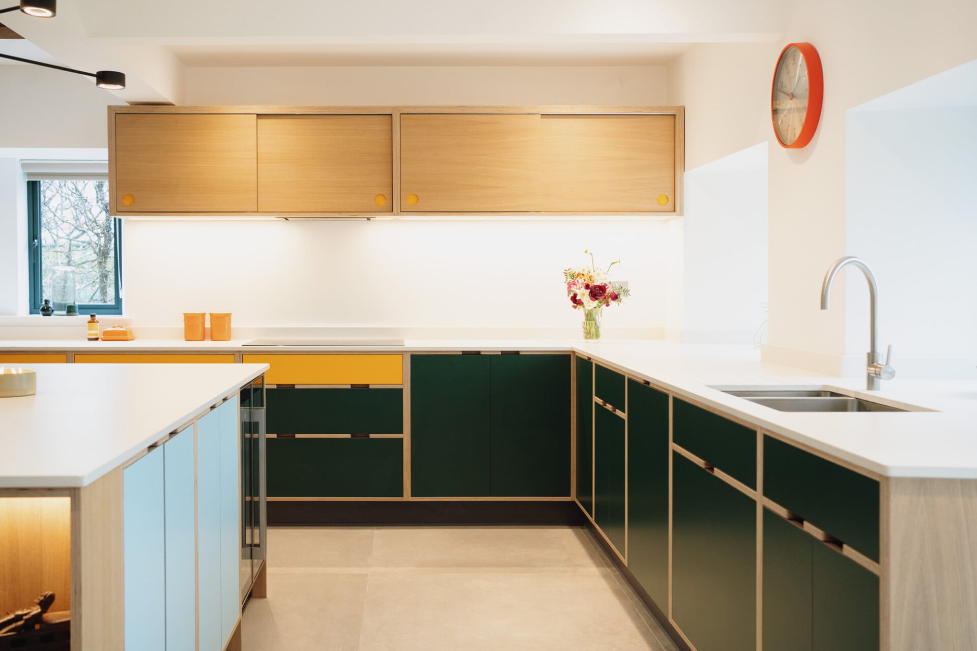 Green and oak plywood kitchen with white worktops