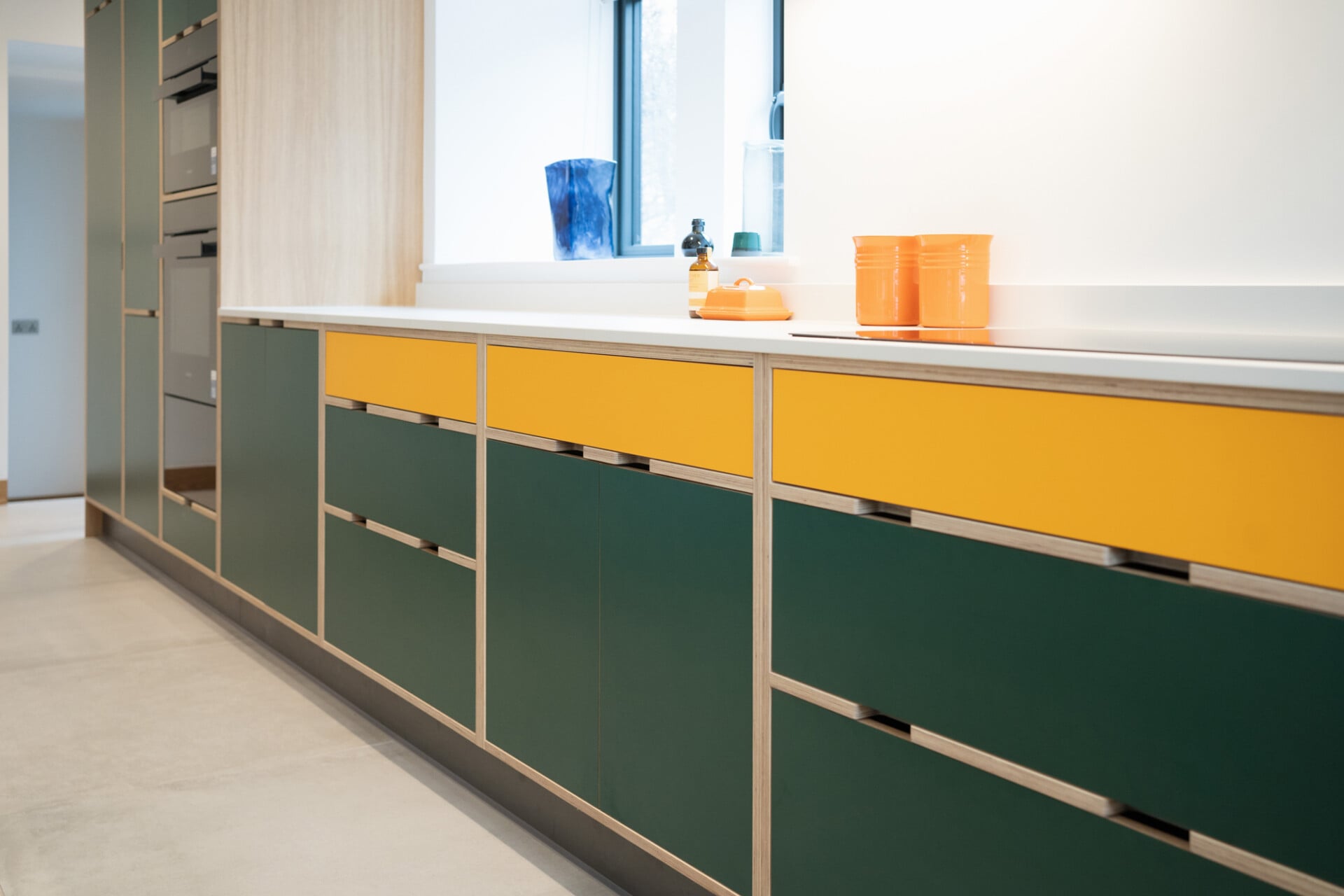Modern green and yellow family kitchen with flat-fronted plywood drawers