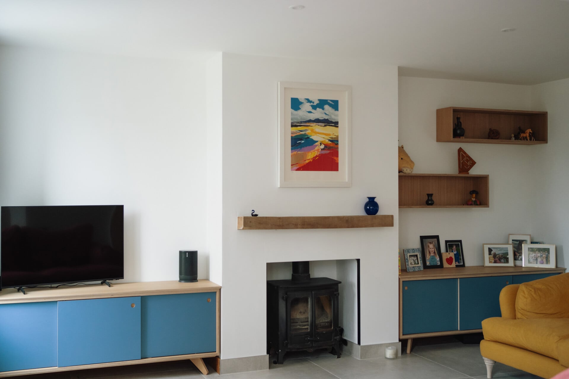 Living room with built-in plywood cabinets, blue drawers, and family fireplace