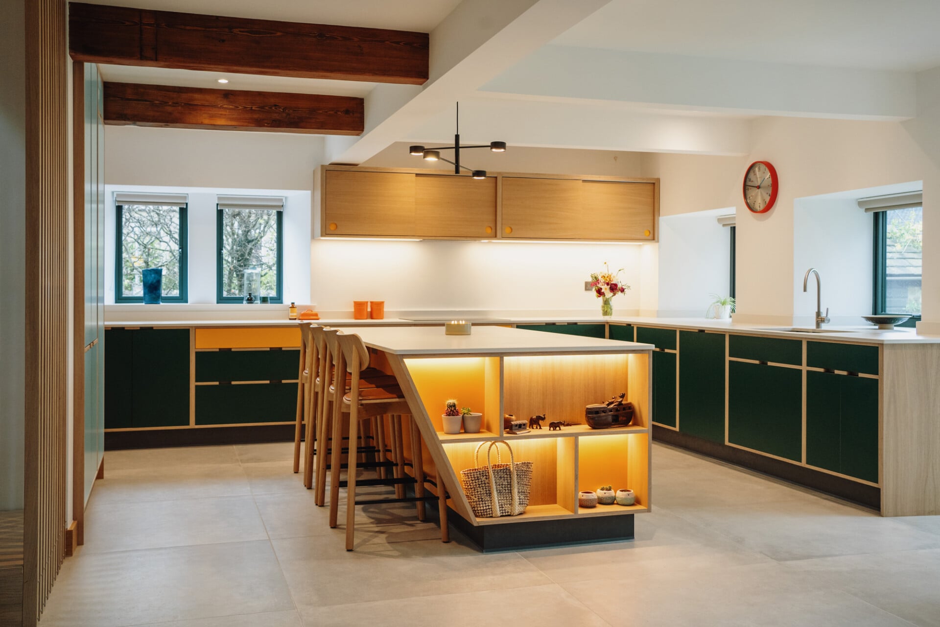 Colourful kitchen with green base cabinets, oak uppers, and open plan layout