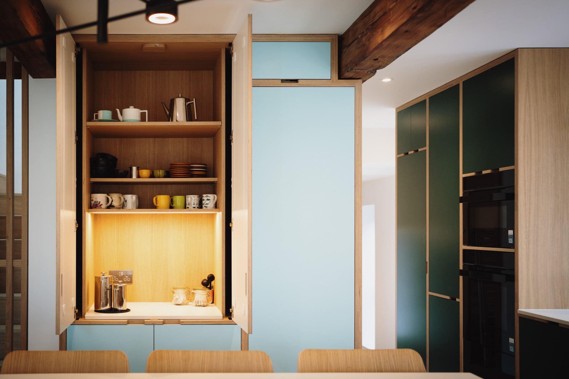 Open pantry nook with concealed shelving, soft lighting, and blue accents